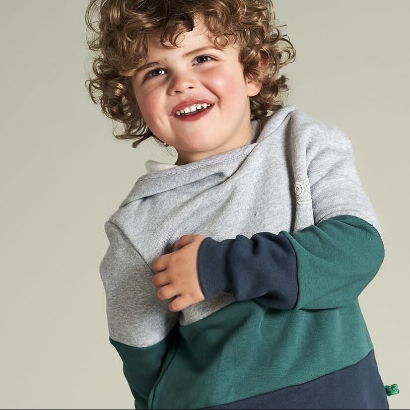 Little boy wearing a grey, green, and blue toned organic sweatshirt